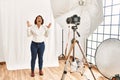 Middle age hispanic woman posing as model at photography studio celebrating victory with happy smile and winner expression with Royalty Free Stock Photo