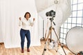 Middle age hispanic woman posing as model at photography studio very happy and excited doing winner gesture with arms raised, Royalty Free Stock Photo