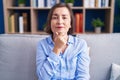 Middle age hispanic woman sitting on the sofa at home looking confident at the camera with smile with crossed arms and hand raised Royalty Free Stock Photo