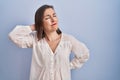 Middle age hispanic woman standing over blue background suffering of neck ache injury, touching neck with hand, muscular pain Royalty Free Stock Photo