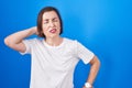 Middle age hispanic woman standing over blue background suffering of neck ache injury, touching neck with hand, muscular pain Royalty Free Stock Photo