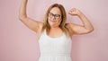 Middle age hispanic woman tired stretching arms over isolated pink background