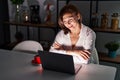 Middle age hispanic woman using laptop at home at night happy face smiling with crossed arms looking at the camera Royalty Free Stock Photo