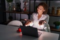 Middle age hispanic woman using laptop at home at night looking at the camera smiling with open arms for hug Royalty Free Stock Photo
