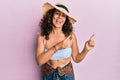 Middle age hispanic woman wearing bikini and summer hat smiling and looking at the camera pointing with two hands and fingers to Royalty Free Stock Photo