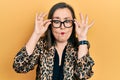 Middle age hispanic woman wearing business clothes and holding glasses making fish face with mouth and squinting eyes, crazy and Royalty Free Stock Photo