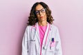 Middle age hispanic woman wearing doctor uniform and glasses relaxed with serious expression on face Royalty Free Stock Photo