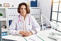 Middle age hispanic woman wearing doctor uniform and stethoscope at the clinic relaxed with serious expression on face Royalty Free Stock Photo