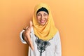 Middle age hispanic woman wearing traditional islamic hijab scarf smiling friendly offering handshake as greeting and welcoming