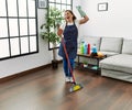 Middle age hispanic woman working as housekeeper dancing at home Royalty Free Stock Photo