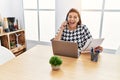 Middle age hispanic woman working at the office with laptop speaking on the phone afraid and shocked with surprise and amazed Royalty Free Stock Photo