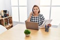 Middle age hispanic woman working at the office with laptop speaking on the phone smiling looking to the side and staring away Royalty Free Stock Photo