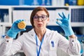 Middle age hispanic woman working at scientist laboratory making vitamin making fish face with mouth and squinting eyes, crazy and