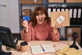 Middle age hispanic woman working at small business ecommerce holding credit card smiling and laughing hard out loud because funny Royalty Free Stock Photo