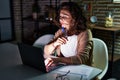 Middle age hispanic woman working using laptop at night at home