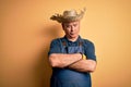 Middle age hoary farmer man wearing apron and hat over isolated yellow background skeptic and nervous, disapproving expression on