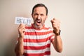Middle age hoary man holding paper with help message over isolated white background annoyed and frustrated shouting with anger, Royalty Free Stock Photo
