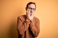 Middle age hoary man wearing brown sweater and glasses over isolated yellow background Tired hands covering face, depression and