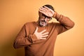 Middle age hoary man wearing brown sweater and glasses over isolated yellow background Touching forehead for illness and fever,