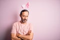 Middle age hoary man wearing bunny ears standing over isolated pink background skeptic and nervous, disapproving expression on Royalty Free Stock Photo