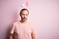 Middle age hoary man wearing bunny ears standing over isolated pink background skeptic and nervous, frowning upset because of Royalty Free Stock Photo