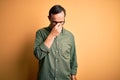 Middle age hoary man wearing casual green shirt and glasses over isolated yellow background tired rubbing nose and eyes feeling Royalty Free Stock Photo