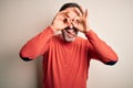 Middle age hoary man wearing casual orange sweater standing over isolated white background doing ok gesture like binoculars