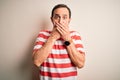 Middle age hoary man wearing casual striped t-shirt standing over isolated white background shocked covering mouth with hands for Royalty Free Stock Photo