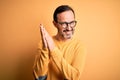 Middle age hoary man wearing casual sweater and glasses over isolated yellow background clapping and applauding happy and joyful, Royalty Free Stock Photo