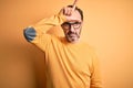 Middle age hoary man wearing casual sweater and glasses over isolated yellow background making fun of people with fingers on