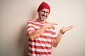 Middle age hoary man wearing striped t-shirt glasses and cap over isolated white background amazed and smiling to the camera while Royalty Free Stock Photo