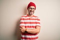 Middle age hoary man wearing striped t-shirt glasses and cap over isolated white background happy face smiling with crossed arms Royalty Free Stock Photo