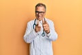 Middle age indian man wearing doctor coat and stethoscope pointing fingers to camera with happy and funny face Royalty Free Stock Photo