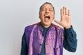 Middle age indian man wearing traditional indian clothes shouting and screaming loud to side with hand on mouth