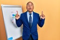 Middle age latin man wearing business clothes on chart presentation amazed and surprised looking up and pointing with fingers and Royalty Free Stock Photo