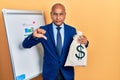 Middle age latin man wearing business suit holding dollars bag with angry face, negative sign showing dislike with thumbs down, Royalty Free Stock Photo