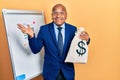 Middle age latin man wearing business suit holding dollars bag celebrating victory with happy smile and winner expression with Royalty Free Stock Photo