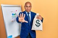 Middle age latin man wearing business suit holding dollars bag with open hand doing stop sign with serious and confident Royalty Free Stock Photo