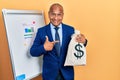 Middle age latin man wearing business suit holding dollars bag smiling happy pointing with hand and finger Royalty Free Stock Photo