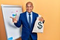 Middle age latin man wearing business suit holding dollars bag smiling happy pointing with hand and finger to the side Royalty Free Stock Photo