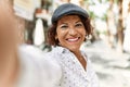 Middle age latin woman smiling happy making selfie by the camera at the city