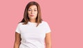 Middle age latin woman wearing casual white tshirt relaxed with serious expression on face