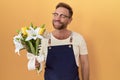 Middle age man with beard florist shop holding flowers smiling looking to the side and staring away thinking Royalty Free Stock Photo