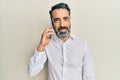 Middle age man with beard and grey hair having conversation talking on the smartphone looking positive and happy standing and Royalty Free Stock Photo