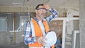 Middle age man builder holding hardhat sweating at construction site Royalty Free Stock Photo
