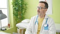 Middle age man doctor sitting with serious expression at clinic