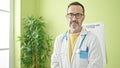 Middle age man doctor standing with serious expression at clinic