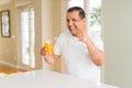 Middle age man drinking a glass of orange juice at home happy with big smile doing ok sign, thumb up with fingers, excellent sign Royalty Free Stock Photo