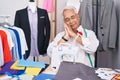 Middle age man with grey hair dressmaker using sewing machine sleeping tired dreaming and posing with hands together while smiling Royalty Free Stock Photo