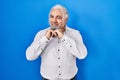Middle age man with grey hair standing over blue background laughing nervous and excited with hands on chin looking to the side Royalty Free Stock Photo